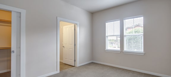 a bedroom with two windows and an open door