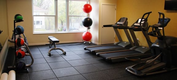Fitness Room with rubber flooring, two treadmills, and medicine ball rack
