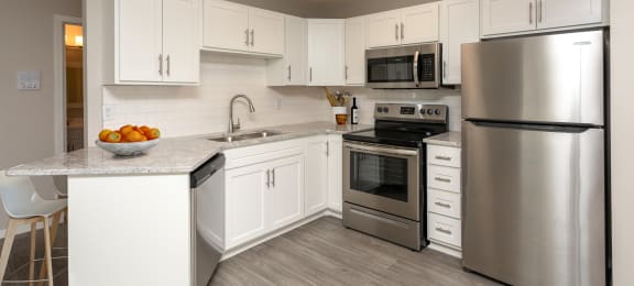 Kitchen with white cabinets, stainless steel appliances and grey wood floors