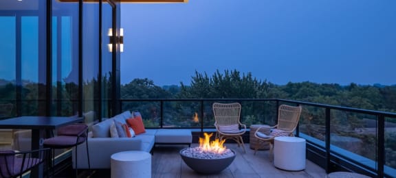 a patio with a fire pit and chairs on a balcony