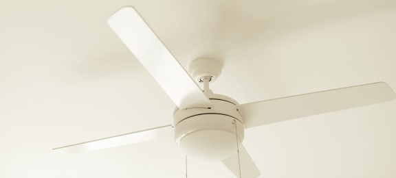 a white ceiling fan hanging from a ceiling with a window in the background