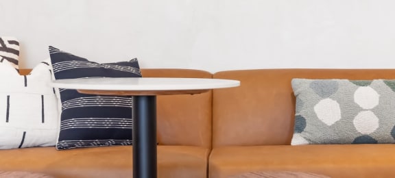 a table and two stools in front of a brown couch