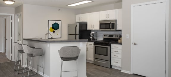 Modern kitchen with open layout, stainless steel appliances, and white cabinetry.