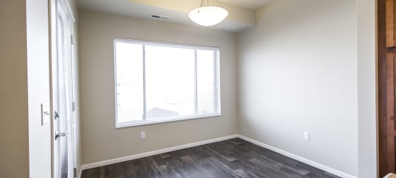 an empty living room with a large window and wood flooring