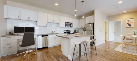 Spacious modern kitchen with white cabinetry, stainless steel appliances, and pendant lighting above the island. Kitchen opens up into separate dining area.