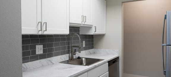 a kitchen with white cabinets and a stainless steel sink