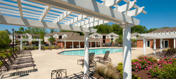 Pergola, tables and chairs overlooking swimming pool and floral landscaping