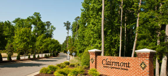 Tree-lined street with Clairmont Apartments sign leading into the community