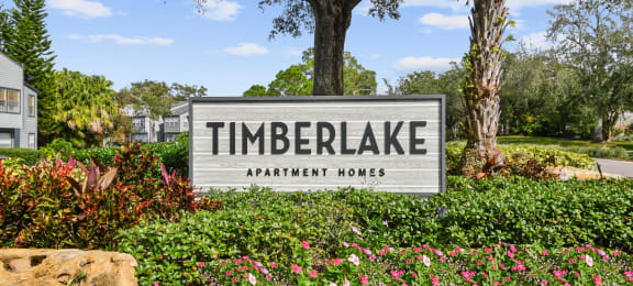 a sign for timbrelake apartment homes in front of plants and trees