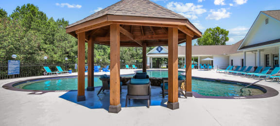a gazebo with a grill next to a pool
