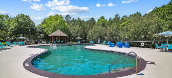 a resort style pool with chaise lounge chairs and a gazebo