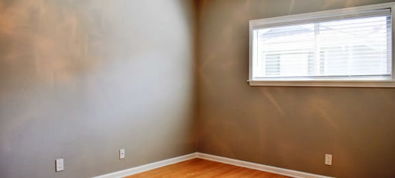 View of bedroom with wood look flooring, well lit window, and ceiling fan