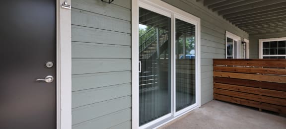 Outside view of front door, sliding glass door to patio, and privacy fence
