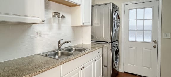 kitchen with granite counters, wood floors, and stacked washer dryer