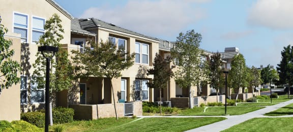 a row of apartments on a sidewalk with grass and trees
