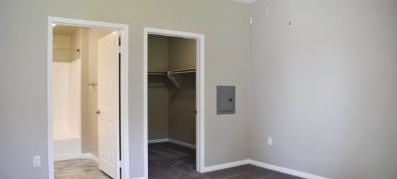 Bedroom looking into walk in closet and en suit bathroom. Has carpet flooring in bedroom and tile flooring in bathroom