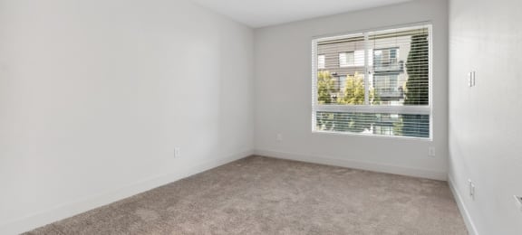 an empty living room with a window and carpet