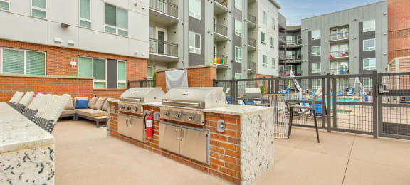 an outdoor patio with a barbecue grill and a pool in front of an apartment building