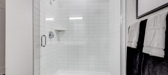 a white shower with white tiles in a bathroom
