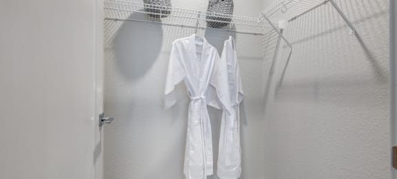 a walk in closet with two white robes hanging on a rack