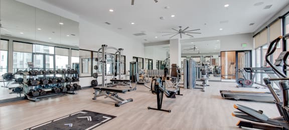 a spacious fitness center with weights and cardio equipment and large windows