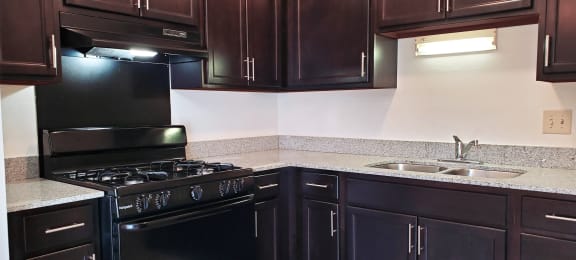 Kitchen in a 1 bedroom apartment with black appliances and dark wood cabinets at Carriage House West.