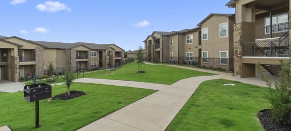 a view of an apartment complex with a green lawn and sidewalk