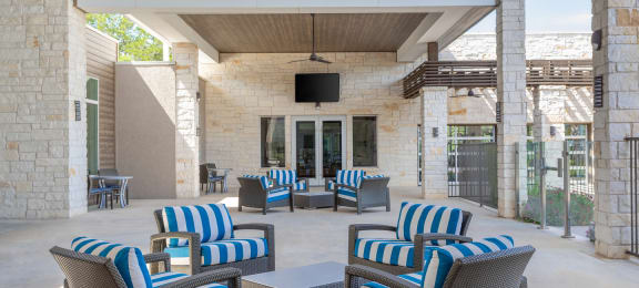 an outdoor patio with blue and white chairs and a television