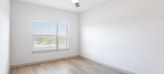 an empty room with white walls and wood floors and a ceiling fan