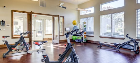 a gym with treadmills and exercise equipment in a room with windows