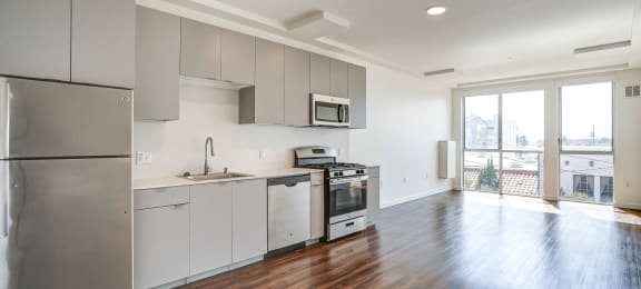 an empty kitchen with gray cabinets and stainless steel appliances