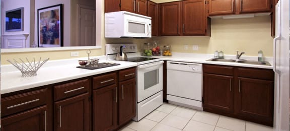 Spacious kitchen with lots of cabinet space, side-by-side refrigerator, porcelain tile floors, and lots of counter space at The Biltmore Apartments in Omaha, Nebraska