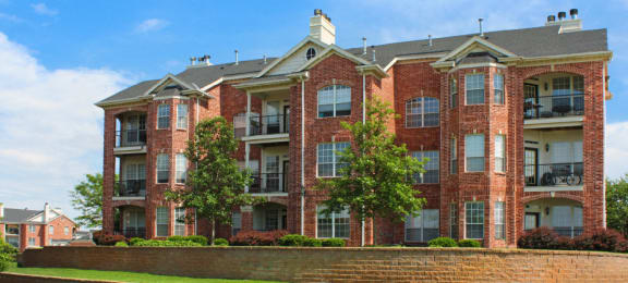 Luxury apartments with red brick exterior, spacious balconies, lush landscaping, and scenic views at Lenox Village Apartments in Lincoln, Nebraska