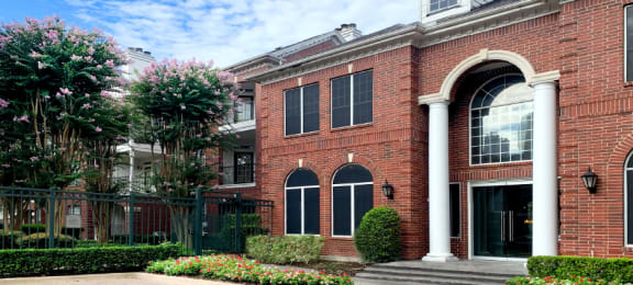 Luxury apartments with brick exteriors and lush landscaping at Tuscany Apartments in Houston.