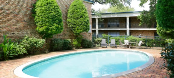Apartments near the Galleria with multiple swimming pools, sun deck with poolside lounge chairs, brick exteriors and courtyard setting at Plantation apartments in Houston.