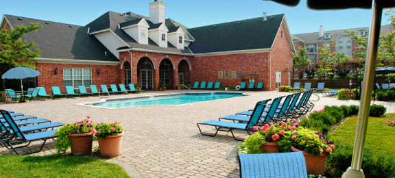 Luxury apartments with swimming pool, poolside lounge chairs, picnic area, grilling station, lush landscaping, and scenic views at Lenox Village Apartments in Lincoln, Nebraska