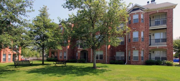 Luxury apartments with red brick exterior, spacious balconies, lush landscaping, park-like setting, and scenic views at Lenox Village Apartments in Lincoln, Nebraska