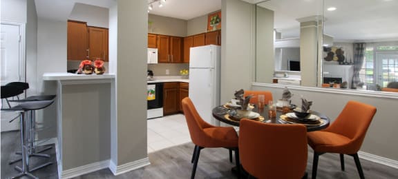 Luxury apartments with wood grain plank floors, dining room, u-shaped kitchen, mirror accent wall, and breakfast bar at Lenox Village Apartments in Lincoln, Nebraska