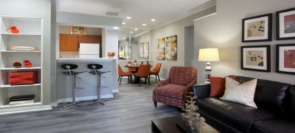 Luxury apartments with wood grain plank floors, dining room, u-shaped kitchen, mirror accent wall, built-in shelves, and breakfast bar at Lenox Village Apartments in Lincoln, Nebraska