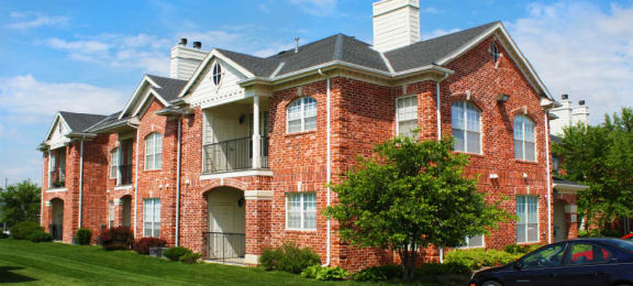 Luxury apartments with red brick exterior, spacious balconies, lush landscaping, park-like setting, and scenic views at Lenox Village Apartments in Lincoln, Nebraska