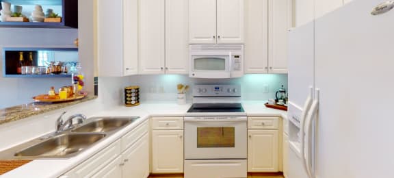 Bright kitchen with granite slab breakfast bar and white cabinets at Tuscany Court Apartments in Houston.