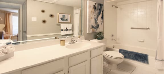 Spacious bathroom with white cabinets and white porcelain tile at Preston Village Apartments in North Dallas