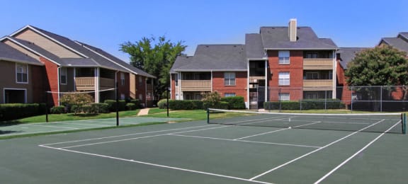Luxury apartments with tennis court, red brick exteriors, beautiful landscaping, and spacious balconies at Preston Village Apartments in North Dallas