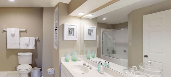 Luxury apartments with spacious bathrooms with glass showers, oval soaking tubs, built-in shelves, spacious linen closets, and cultured marble vanities at Tuscany Gate Apartments in Houston.