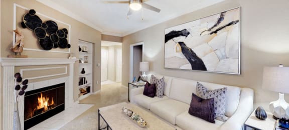 Spacious living room with wood-burning fireplace with glass doors, ceiling fan, crown molding, and built-in bookshelves at Tuscany Gate Apartments in Houston.