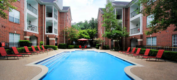 Luxury swimming pool with spacious sundeck, beautiful landscaping, and poolside lounge seating at Tuscany Oaks Apartments in Houston.