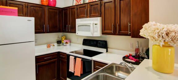 Spacious kitchen with honey brown toned cabinets with modern silver hardware, and white appliances