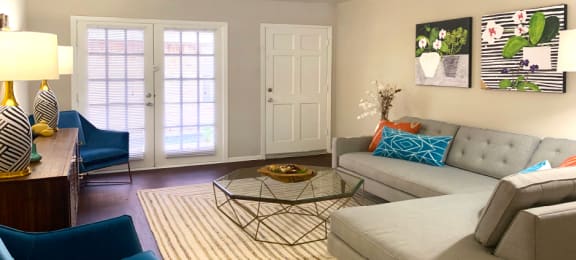 Spacious one and two bedroom floor plans with white brick accent walls, wood plank floors, and French doors at Waters of Winrock Apartments in Houston.