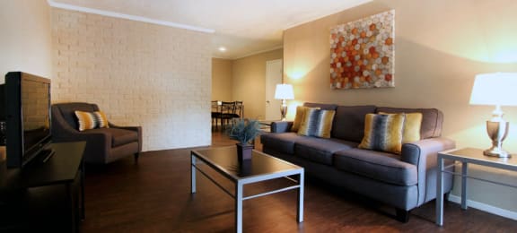 Spacious one and two bedroom floor plans with white brick accent walls and wood plank floors at Waters of Winrock Apartments in Houston.