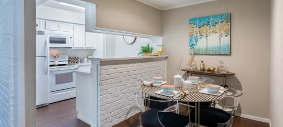 Spacious one and two bedroom floor plans with white brick accent walls and wood plank floors at Waters of Winrock Apartments in Houston
